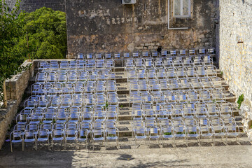 A large open-air theater with neatly arranged folding chairs. The scene is calm and ready for a performance.
