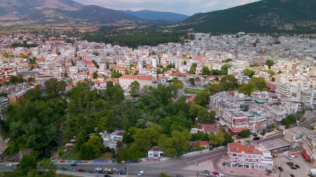Wide aerial drone shot flying over the lush Saint Barbara's Springs Park, highlighting the central green gardens and lakes nestled within the city of Drama, Greece.