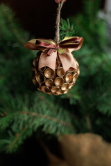 Handmade hanging ornament on green fir branch with clear copy space. Concept of holiday decoration, craft design, card and banner visuals.