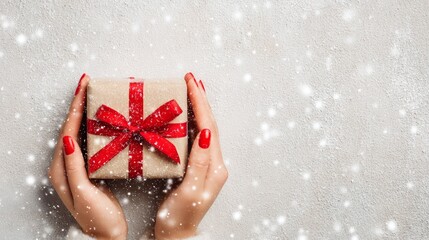 Red manicured hands holding wrapped present with satin bow against snowy background. Elegant Christmas package for festive celebration, birthday surprise or wedding anniversary.