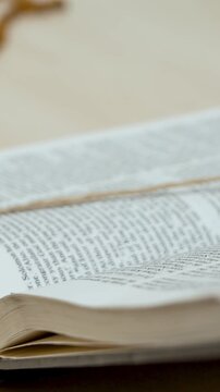 Bible lays on wooden table. Womans hand follows scripture. Finger moves carefully over text. She reads sacred words with focus. Pages hold divine truth. Spiritual connection deepens. Faith inspires