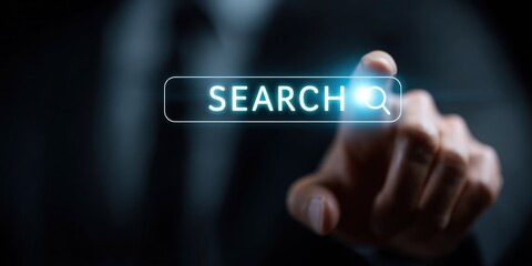 A man is pointing to a search button on a computer screen