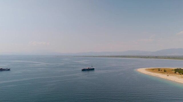Aerial drone view tracking two passenger ferries navigating the clear turquoise waters of the Thracian Sea near Keramoti Beach, Kavala, Greece.