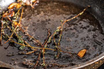Thyme with garlic and spices is fried in oil in a pan. Close-up. High quality photo