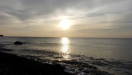 Golden sun setting over calm ocean high resolution photo