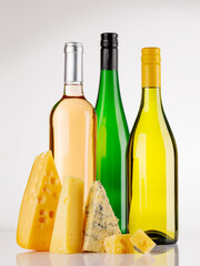 Naklejka premium Assorted cheeses and wine bottles on white background