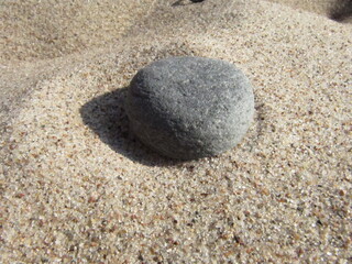 Smooth Round Stone Resting on Sunlit Sand