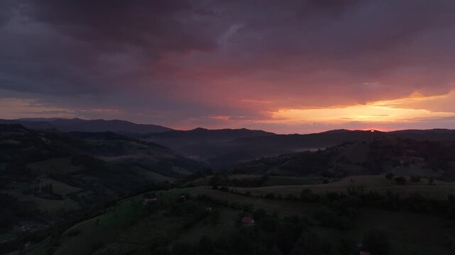 Panoramic view over a Transylvanian mountain valley at sunset after rain, the storm breaks with rising mist, rolling hills, and scattered farmhouses, cinematic and atmospheric early summer evening