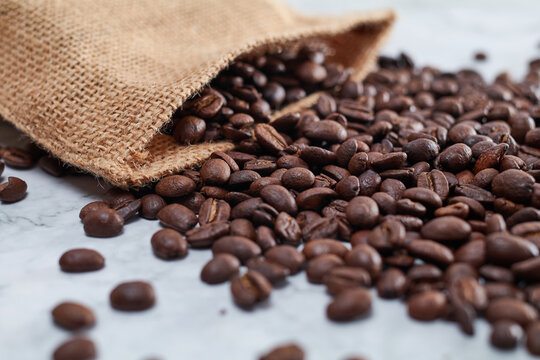Roasted Jamaican Blue Mountain coffee beans coming out of a brown burlap pouch