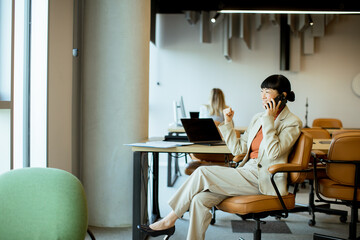 Businesswoman on phone in a modern, collaborative office during work hours