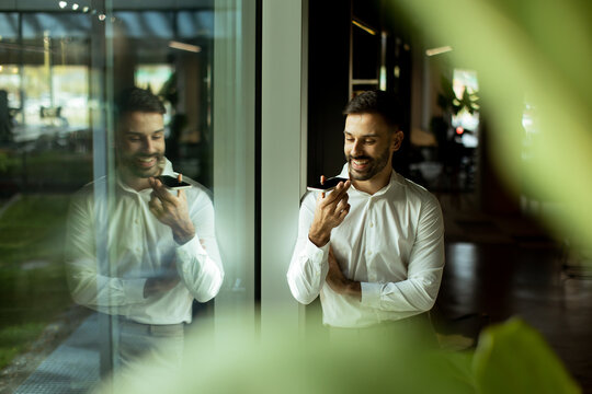 Man engaged in a conversation while standing by a large window in a modern office
