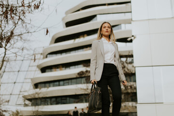 Fototapeta premium Confident businesswoman walking in front of a modern urban building