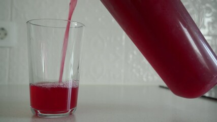 Red liquid is poured from a plastic or glass pitcher into a glass tumbler. The rapid flow of the liquid creates a continuous gushing and pouring sound. - Powered by Adobe