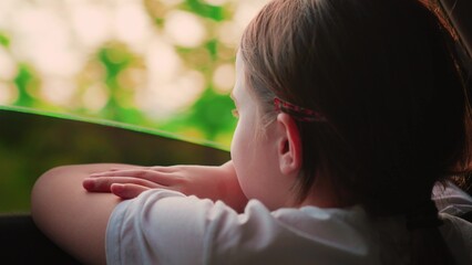 Children's trip. Girl child looks out car window. Family vacation. Girl looks out car window. Happy...
