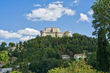 The imposing Forte di San Leo (San Leo Fortress) perched on a steep, forested hill in Italy.