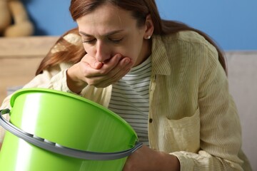 Woman with bucket suffering from nausea at home © New Africa