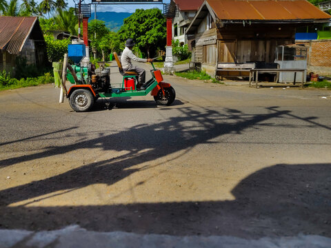 a man is driving a vehicle with a mobile rice milling machine on a rural road
