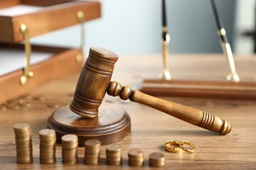 Alimony. Coins, engagement rings and judge's gavel on wooden table against grey background,...