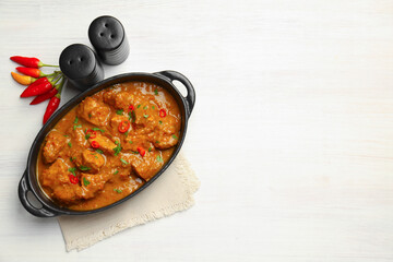 Salt, pepper shakers, chili and chicken tikka masala on wooden table, flat lay. Space for text