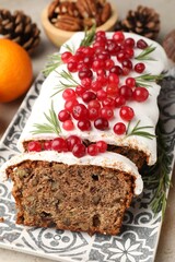 Tasty Christmas cake with icing, cranberries, nuts, tangerine and festive decor on table, closeup