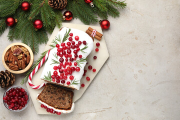 Naklejka premium Tasty Christmas cake with icing, cranberries, nuts and festive decor on light grey table, flat lay. Space for text