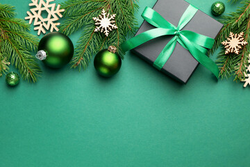 Beautiful Christmas composition with gift and decor on green background, flat lay. Space for text
