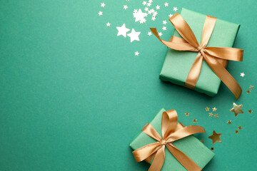 Beautiful Christmas gifts and confetti on green background, flat lay. Space for text