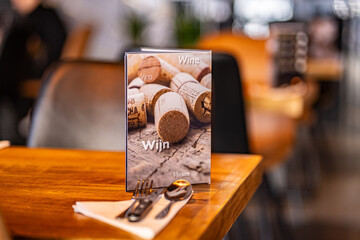 Modern trendy wooden silver appliances - fork and knife on a wooden serving table in the restaurant with a wine card