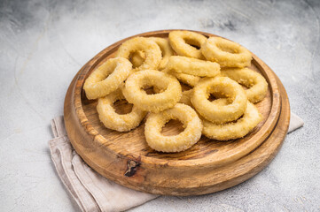 Raw onion rings on wooden board. grey background. top view
