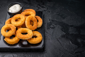 Deep fried squid rings with breading, calamari fastfood snack. black background. top view