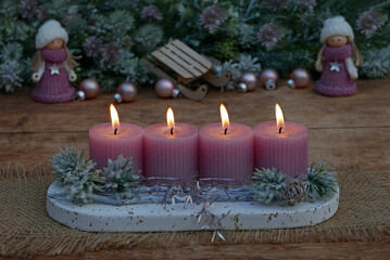 Fourth Advent: Advent arrangement with pink candles, Christmas decorations and small dolls.