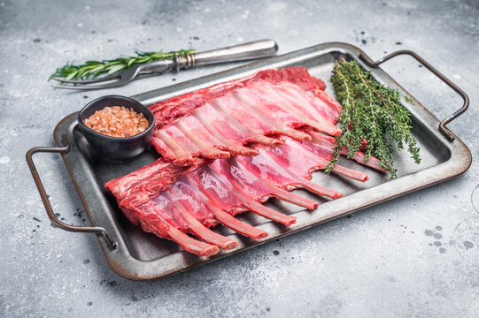 Raw mutton meat for chops steaks, uncooked rack of lamb on steel tray with herbs. grey background. top view - Powered by Adobe