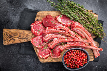 Raw mutton cutlets, fresh lamb meat chops on a wooden board. black background. top view