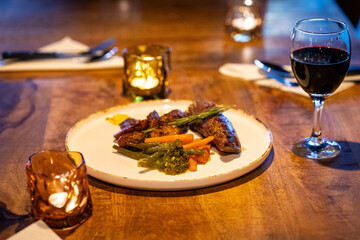 Beef steak meat with vegetables and sauce served with red wine and candles