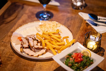 Plate with Gyros meat, pita bread, side salad and french fries on table in Greek restaurant kitchen
