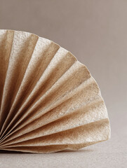 Minimalist still life highlighting texture and form. A folded paper element suggests preparation, filtering, or organic processes. Warm, neutral color palette.