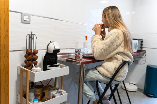 Young woman eating breakfast at home kitchen table