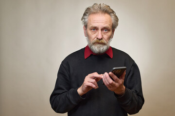 Old man over 60 portrait in studio with smartphone