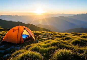 Orange tent pitched on a grassy mountain ridge at sunrise