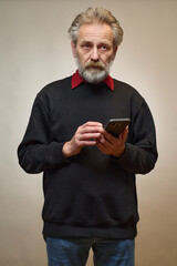 Old man over 60 portrait in studio with smartphone