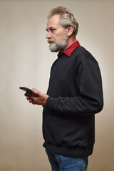 Old man over 60 portrait in studio with smartphone