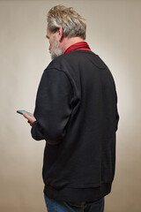 Old man over 60 portrait in studio with smartphone