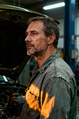 Automotive technician inspecting vehicle in service workshop during evening hours