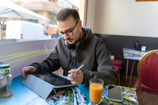 Man working with tablet in cafe remotely - Powered by Adobe