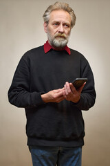 Old man over 60 portrait in studio with smartphone