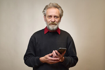 Old man over 60 portrait in studio with smartphone