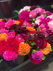 Vibrant Dahlia Flower Bouquet in Bright Summer Colors; a colorful dahlia bouquet arranged in a flower shop, showcasing bright pink, orange, red, and magenta blooms