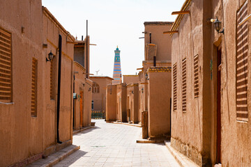 Old quaint street overlooked by the Juma Minaret (Friday Mosque Minaret) in Ichan Kala, the Old City of Khiva in Uzbekistan, Central Asia