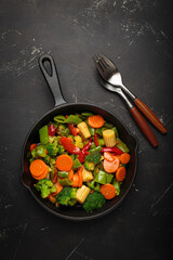 Colorful vegetables broccoli carrot green beans bell pepper stir fried in a cast iron skillet,...