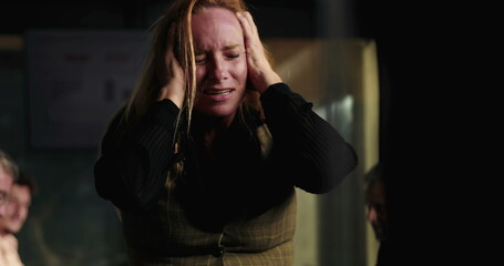 Blonde businesswoman in visible emotional breakdown during office meeting, holding head with both...